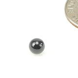 Small black bearing ball next to coin for scale