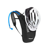 Black CamelBak hydration pack with blue tube paired with white Giro bike helmet for mountain biking