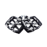 A pair of black bicycle pedals with a white diagonal stripe pattern, displayed on a clean white background.
