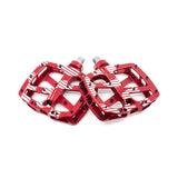 A pair of red metal bicycle pedals with a white and black diagonal stripe pattern, displayed on a clean white background.