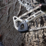 UPP mountain bike derailleur hanger with chain and cassette against tree bark